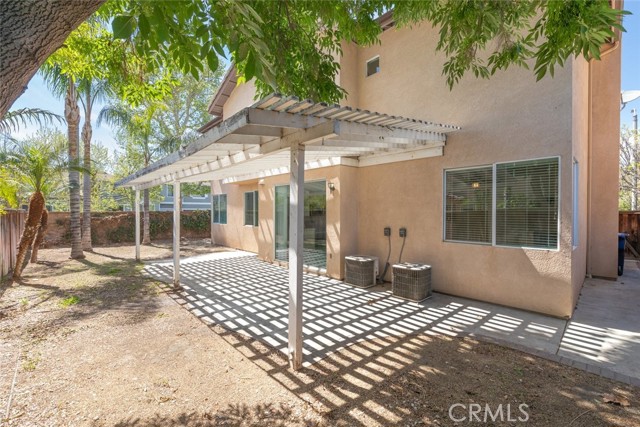 A larger backyard with covered patio and mature trees