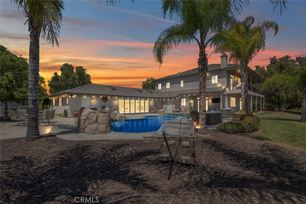 Welcome to the ultimate getaway in the heart of Temecula Wine Country—a breathtaking estate offering 6,550 sq ft of luxurious living on approximately five fully fenced private acres. This stunning property includes a remodeled 4,950 sq ft main house and a sleek 1,600 sq ft guest house, surrounded by rolling hills and world-renowned vineyards. A tree-lined driveway leads to a rose garden and charming gazebo, setting the tone for the elegance within.

Inside, a grand iron door opens to a sweeping staircase and luxury vinyl plank flooring throughout. The main house features five spacious bedrooms, two private offices, and an open-concept layout ideal for entertaining. The kitchen boasts quartz countertops, an oversized island, Sub-Zero fridge, and a Mercury 48" induction oven. A wet bar and large dining area enhance the experience, while a main-floor guest suite offers privacy for visitors.

Upstairs, the primary suite offers a fireplace, French doors to a balcony, and a spa-inspired bathroom with marble counters and soaking tub. The guest house features a stylish kitchen, stacked stone fireplace, great room, and sliding glass doors that open to the pool. Outdoors, enjoy a resort-style pool and spa, fruit orchard, garden beds, solar system, generator, and panoramic views—just minutes from top wineries.