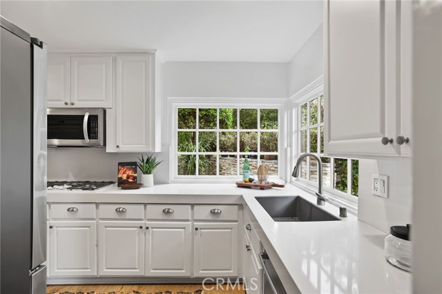 The kitchen features stainless steel appliances and a delightful breakfast nook, with a sliding glass door for easy access to the side patio and BBQ area.