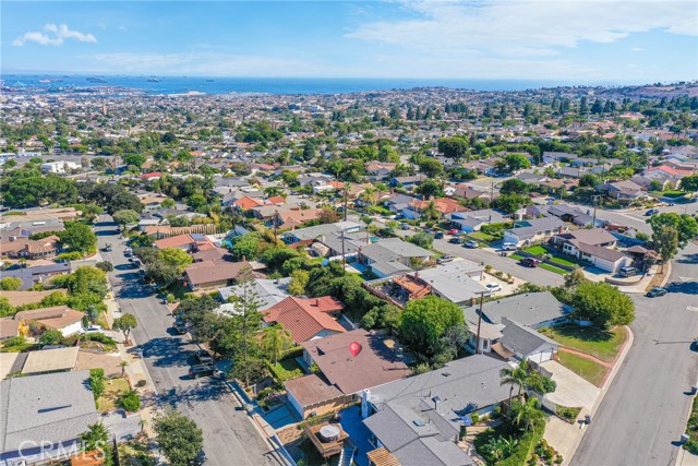 Drone view of home, wide, quiet street with ocean in background