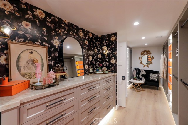 The expansive boutique style primary walk-in closet features abundant storge, custom built-ins, and a striking Onyx countertop.