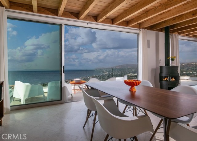 1119 Katella Street Laguna Beach, California Beautifully designed by an award winning Laguna Beach architect, this contemporary home boasts mesmerizing panoramic ocean views spanning the entire coastline from every main room of the house. Walls of sliding glass pocket doors disappear and the spacious decks expand indoor living to outdoors with ease. This home is fully furnished with mid-century flair and showcases stunning artwork throughout. The upper level great room is enhanced by high open beamed ceilings that create a chic loft-style feel. The chef’s kitchen is outfitted with a Wolf oven, commercial grade refrigeration, stainless steel counter tops and an island designed for effortless entertaining. The living area is a relaxing retreat with a Rais stove and smart TV. A powder room, pantry and computer workspace completes the upper level. The exquisite master suite comes complete with king bed, seating, smart TV, fireplace and the stunning ocean view is center stage. The master bath offers a double vanity, soaking tub, walk-in shower for two, generous sized walk-in closet and separate vanity area. The second bedroom has a queen bed, club chair, large closet, smart TV and adjacent full bath with shower and tub. A private entry courtyard with seating offers the perfect place to sequester. The home is 100% solar powered and is filled with an abundance of natural light. Enjoy beach living and all the luxuries of this turn-key modern coastal home.