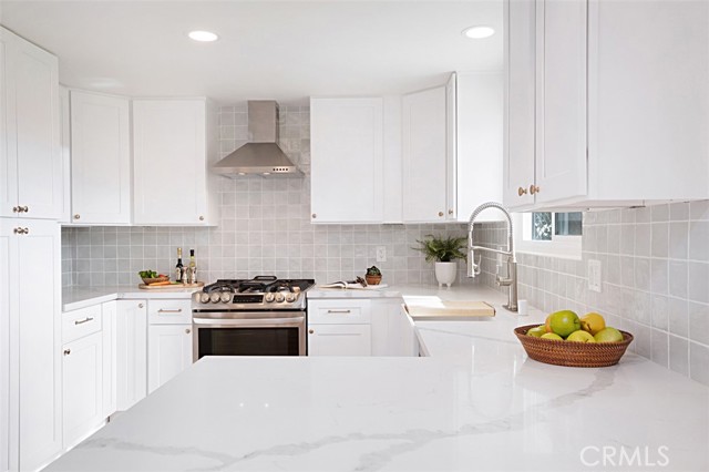 Beautifully updated kitchen with quartz counter-tops, custom back splash, and stainless-steel appliances.