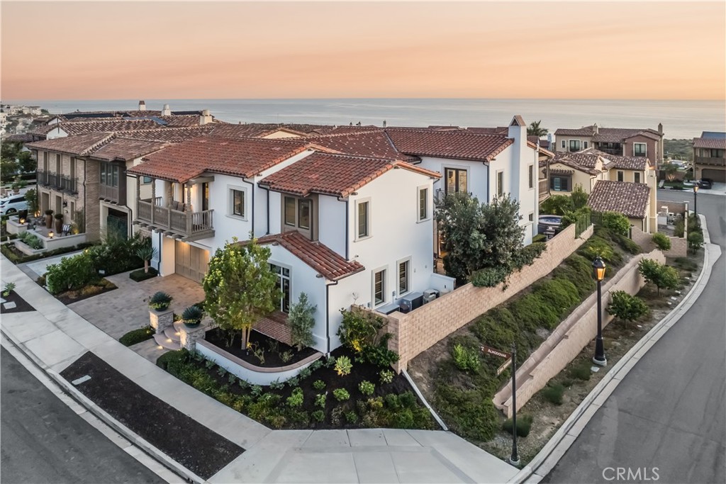 Nestled within the sought-after enclave of Sea Summit, this exceptional residence offers a composition of ocean views, privacy, and luxurious interiors. Full of gentle Pacific breezes, the home features a seamless blend of elegant indoor spaces and multiple outdoor areas, creating the ultimate coastal living experience. An array of refined, high-end materials has been expertly interwoven throughout this spacious five-bedroom property, creating a tranquil haven. The main level connects to the outside via multiple sets of folding doors, fully inviting the exteriors in. A tiered, oversized eat-in island anchors the great room, which encompasses the informal dining area and living section with a fireplace. The entirety of the space is accented by rich wooden beams. The kitchen, the heart of the home, offers both form and function. A suite of high-end appliances blends seamlessly into the two-tone cabinetry while the butler’s pantry supplies additional storage and counter work space. The private, lushly landscaped backyard with a solar-heated pool and hot tub provides more entertaining options, with a fire pit and a fully equipped outdoor kitchen. A coveted and peaceful ground floor bedroom, complemented by an en-suite bath, completes this level. Exquisite design elements continue upstairs: the ocean-view primary suite features shiplap details, a large balcony, and doors on opposite walls to allow enjoyment of cross-breezes from the coastline. Pacific vistas extend into the adjacent bathroom, which is bright and opulent, with a large soaking tub, oversized shower, and walk-in closet. A versatile bonus room on this floor can serve multiple functions, while the secondary bedrooms, each with en-suite bathrooms, offer great sleeping quarters. Revered for its location as well as amenities, Sea Summit features a community clubhouse with a pool and spa, and easy access to miles of hiking trails, the area’s beaches, and lively downtowns of San Clemente and Dana Point.