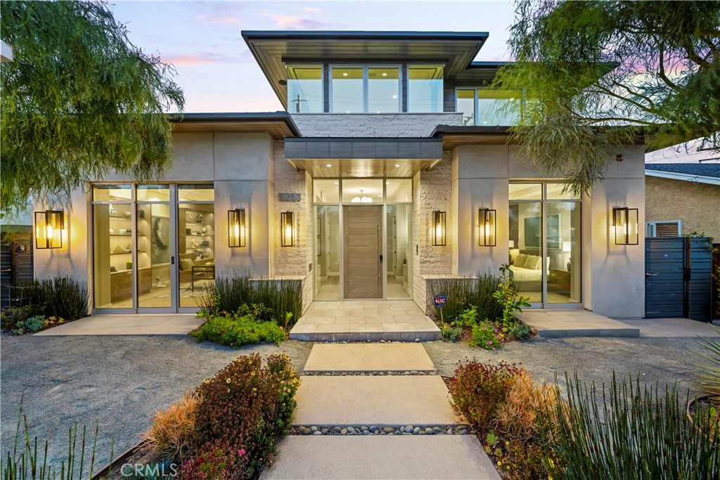Nestled into the scenic Hill Section of Manhattan Beach lies 763 11th Street, a 4,900 square-foot home designed by Louie Tomaro and expertly constructed by Mike Davis Custom Homes in 2018.  This modern splendor design is perfectly executed, offering a rare combination of tailored, traditional design elements with a modern flair. Soaring Fleetwood doors and windows throughout including disappearing patio doors on the first floor present seamless indoor/outdoor living.  An interior courtyard boasts a Zen-style pool, spa, and water feature, indicating a lovely private area for open-air entertaining.  The outdoor dining room comes complete with built-in bar, towering stone fireplace, modern pendants and flush-mount heaters for dining al fresco.  The Chef’s kitchen is replete with an expansive custom Neolith island, charming breakfast nook, a gorgeous statement ceiling and brass pendants as well as Thermador and Miele appliances. The open-plan living and dining areas include a floating travertine fireplace, automated shades, and built-in cabinetry.  A guest suite with striking full bath, laundry room, pool bath and library with spacious bookcases complete the first floor.  The stairwell is an artistic focal point of the home, adjacent to the 3-stop elevator and comprised of a split-face limestone accent wall, floating staircase, and oversized skylights that bathe the area in abundant natural light.  The powder room services both the first and basement floors, and the vast garage provides space for storage and parking multiple vehicles.  The basement also boasts a theater room, fully equipped with a 4K home theater system as well as a 360-bottle wine cellar. Upstairs, double doors lead to the Master Bedroom, featuring a black Neolith fireplace, patio doors fronting a balcony overlooking the serene courtyard below, and a custom walk-in closet with charming detail. The Master bath offers a freestanding sculptural bathtub, rain shower and dual sinks.  Two additional bedrooms feature charming en suite baths and roomy closets, and a full-size laundry room with custom shelves and sink is conveniently located on the second floor as well.  A beautifully-positioned front office, den or additional guest suite includes a ¾ bath with shower, travertine bar with beverage center, and extensive windows in addition to an inviting deck, taking advantage of scenic ocean, hillside and mountain views.