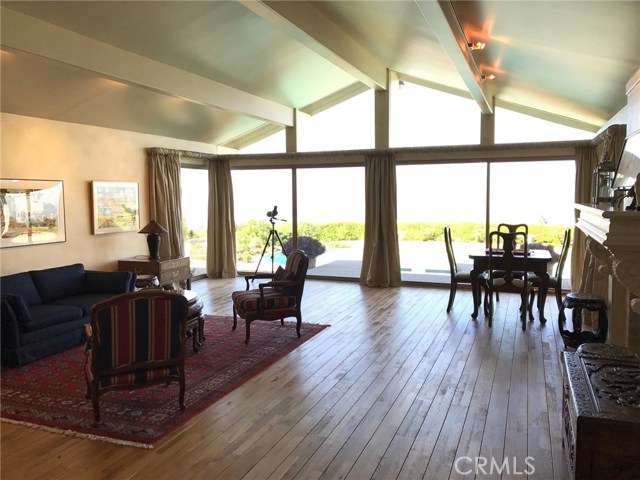 Another view of the living room with panoramic views, beautiful natural light, hardwood floors, and a fireplace.