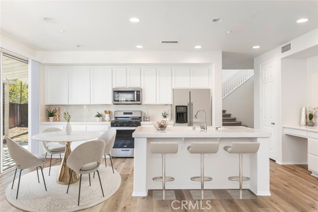 Chefâ€™s kitchen with cabinets and stainless steel appliances give the room a clean, sophisticated edge. A central island, topped with a speckled white countertop, features bar seating for casual dining. Recessed lighting ensures the room is well-lit