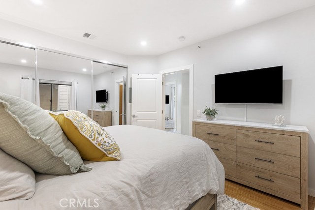 2nd bedroom featuring mirror closet doors and wood flooring