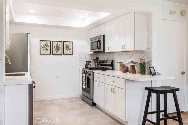 Quartz counter top with breakfast bar seating, in this lovely remodeled kitchen.