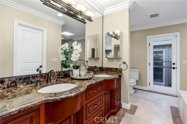 An elegant en-suite bath with gorgeously tiled and frameless oversized shower, soaking tub and the vanity with dual sinks.