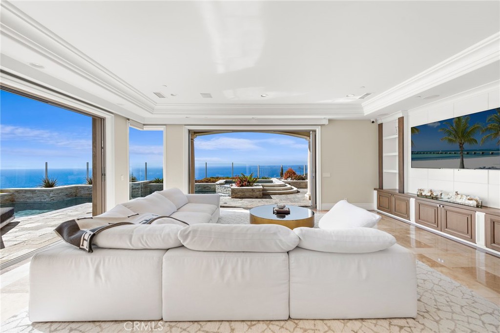 Welcome to 31821 Monarch Crest, an architectural masterpiece in the exclusive guard-gated community of Pinnacle at Monarch Point in Laguna Niguel. Perched on a 0.73-acre lot with breathtaking panoramic ocean views of Laguna Beach and Catalina Island, this 7,796 sq. ft. estate is the epitome of coastal luxury. Featuring six ensuite bedrooms and a total of nine bathrooms, this home is designed for the finest in elegance and comfort. Inside, the main level welcomes you with soaring ceilings, a formal living and dining room, great room with pocket doors that open to the ocean breeze, a custom office with ocean views, ensuite bedroom and a chef’s kitchen equipped with a grand island, Sub-Zero refrigerators, wine refrigerator, coffee bar, and pantry. The upper level is home to the lavish primary suite, offering a private retreat area, dual closets, fireplace, spa-like steam shower and breathtaking ocean views, along with three additional ensuite bedrooms. The lower level is designed for ultimate entertainment, featuring a home theater, game room, wine cellar, laundry room, and an additional ensuite bedroom with access to the expansive 2,000 sq. ft. subterranean garage that accommodates up to eight vehicles behind a private gated driveway. A private elevator ensures seamless access throughout the home. The resort-style backyard is an entertainer’s dream, boasting a sparkling pool, spa, fire pit, built-in BBQ island, and a tranquil koi pond, all framed by stunning ocean vistas. Ideally situated near world-renowned beaches, upscale shopping, fine dining, award-winning schools, and scenic trails, this estate embodies luxury coastal living at its finest.