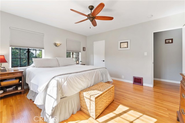 Large main bedroom with walk-in closet, ceiling fan and hardwood floors.