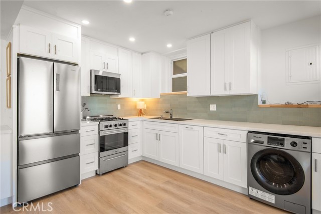 Lower unit kitchen with gleaming cabinetry, quartz counters, stainless appliances, efficiency w/d combo and dishwasher
