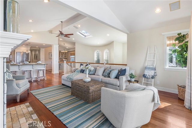Bright and open living room featuring vaulted ceilings, hardwood floors, fireplace and private deck