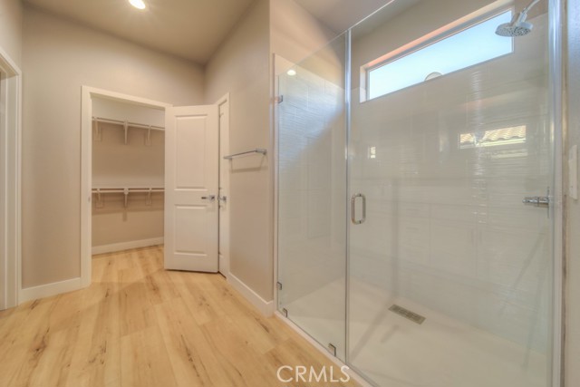 Walk-in shower with frameless shower doors and textured tile wall.