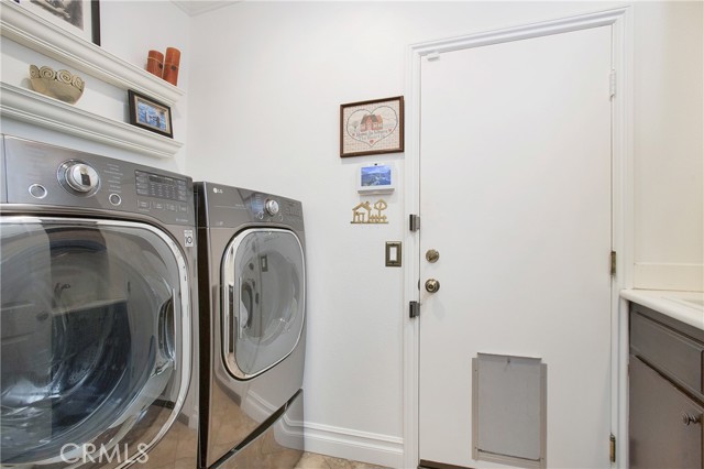 Inside laundry with sink and ample storage leads to garage with epoxy flooring