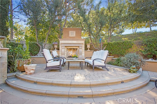 Outdoor living area with custom fireplace mantel and hearth is the perfect place to entertain or warm up after a dip in the pool or spa