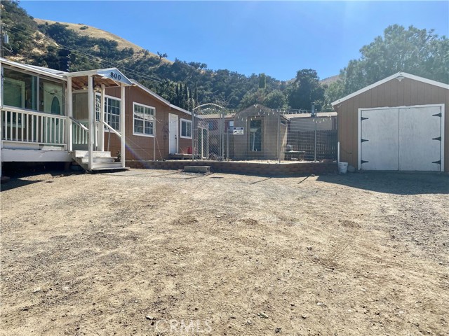 Front of home with parking area, fenced yard, and two sheds.