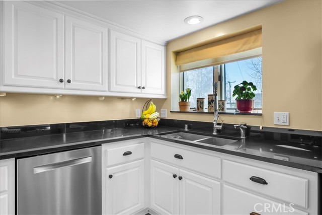 Renovated kitchen with black granite counters and partial ocean view
