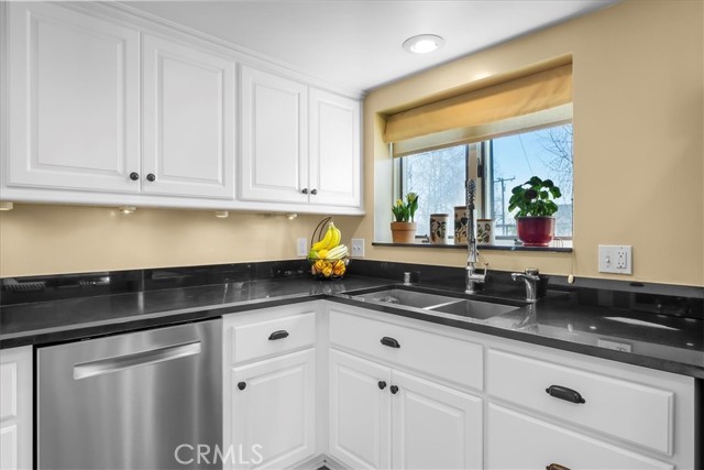 Renovated kitchen with black granite counters and partial ocean view