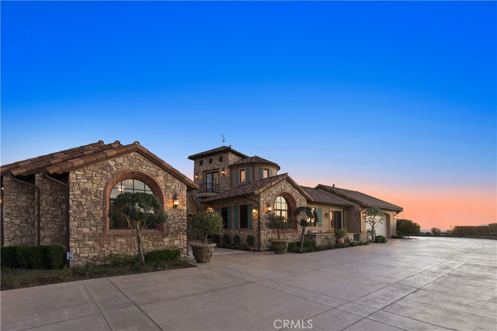 43040 Via Nariz Temecula, California Welcome to “Villa Girasole!”in Temecula. This one of a kind estate is reminiscent of the hill towns of Tuscany in Italy; this truly spectacular home is perched on top of 20 acres (including APN# 935-230-016)through a private gate & long driveway ,avocado grove (approx. 750 trees), olive trees & fruit orchard plus uncompromised panoramic views of city lights, mountains & golf course. This one story home encompasses 8400 sq ft, 5 bdrms, 7 baths, office, theater, tower & CASITA which includes a separate entrance, living room, full bath, kitchen, & bdrm. PLUS 6 car garage. Upon entering the main home through covered dome arch detail the great room has wood beam ceiling, brick fireplace & plenty of natural light, gourmet kitchen features 2 islands, 2 sinks, La Cornue range, built in refrigerator, walk in pantry, bar seating, plus breakfast nook & formal dining room . Amazing home theater has floating wood floor, surround sound, large screen & coffered ceiling, elegant master suite w fireplace & luxurious master bath. The salt water pool & spa are located in the center of the home in the piazza protected from the elements but open to the sky w outdoor projector, large dome rotunda w fireplace & seating plus outdoor BBQ & access to outdoor bathroom/shower. The separate entrance Nexus tower has curved stairs & breathtaking balcony views. Additionally there are 4 tankless water heaters, solar for pool, well w 5000 gallon tank & endless architectural features. This is a must see!