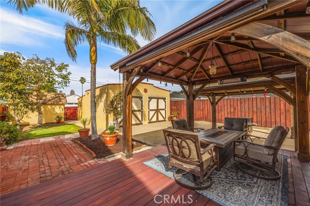 Peaceful backyard with covered deck, lawn area, and gas line for bbq