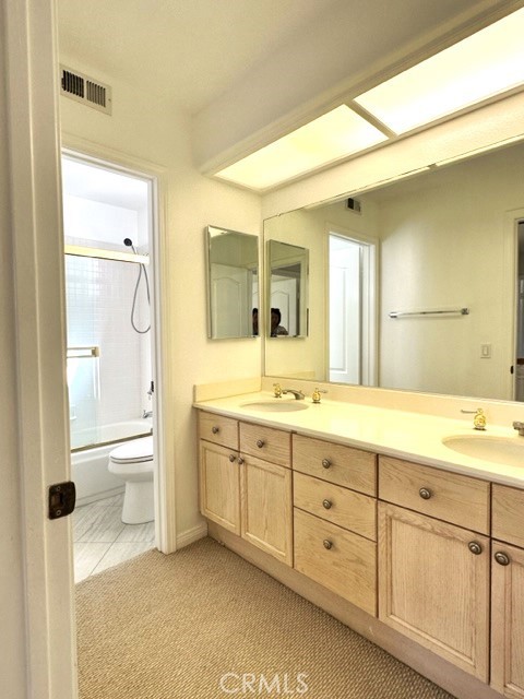 Hall bathroom has double sinks and a separate toilet & bathtub/shower combination with sliding glass door.