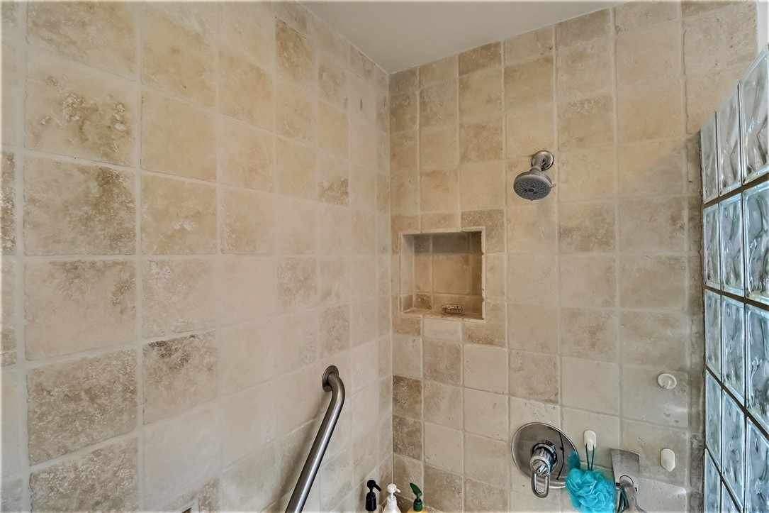 The Custom Shower has Stone Surfaces and A Glass Block Privacy Wall.