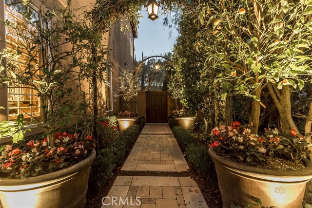 Arched Trellis, lighting and pavers lead to the custom gates and large side yards for storybook feel.