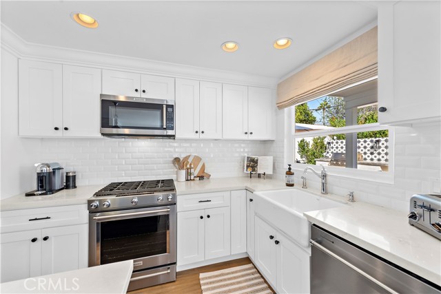 Gas Range, microwave, dishwasher, Kuereg Coffee machine, and apron sink.
