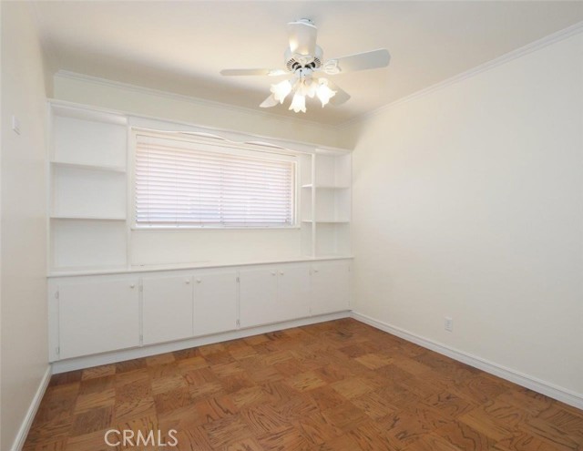 Bedroom 2 with built-ins, white ceiling fan and refinished floors