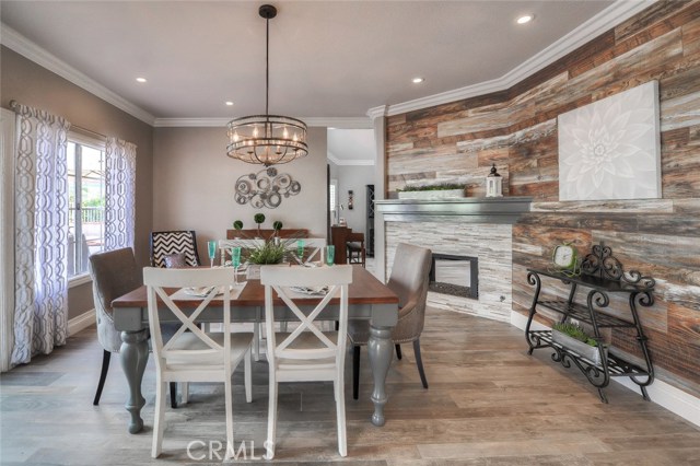 Decorator perfect dining room with stacked stone gas fireplace, re-claimed wood like paneling, tile flooring, recessed lighting, french doors, and crown molding.