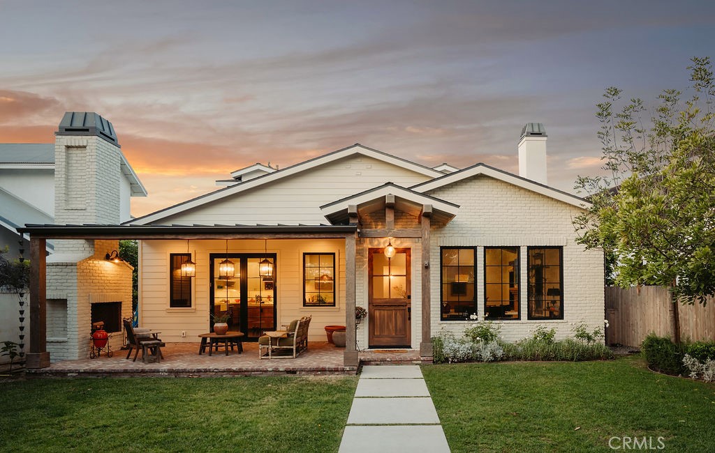A labor of love by Shannon McLaren, founder of Prairie Home Styling, this stunning 4-bedroom, 2.5-bathroom home spans 3,278 sqft on a 6,308 sqft lot, blending California coastal charm with modern traditional aesthetics. Located in the heart of Eastside Costa Mesa, 224 Flower Street has been freshly painted inside and out, offering a warm and inviting atmosphere with impeccable design details throughout. The main living area is a showstopper, featuring vaulted reclaimed white oak ceilings with exposed beams, a striking white brick fireplace with built-in seating, and an abundance of natural light. The open-concept layout seamlessly connects the living and dining spaces, perfect for entertaining or everyday relaxation. A custom-designed bar area boasts hidden beverage storage, an Artillo tile backsplash, and a soapstone countertop. The kitchen is a chef’s dream, with a center island, London Quartz countertops, a built-in banquette, and ample storage. A spacious laundry room on the main level offers full cabinetry and a convenient laundry chute from the second floor. The primary suite is a serene retreat, featuring custom window coverings, a spa-like en suite bath with a soaking tub, dual-head shower, and a well-appointed walk-in closet. Upstairs, a versatile loft provides space for work or play. Three additional bedrooms include a unique walk-in closet currently designed as a kids’ hideaway, with potential for future conversion into an en suite bath. A large secondary bathroom features a dual vanity, quartz counters, and limestone flooring. Modern amenities include zoned A/C, two tankless water heaters, built-in speakers, an oversized two-car garage with EV charging, and conduit for future solar. Outside, a covered brick patio with a fireplace, mature citrus trees, and privacy hedges create a perfect outdoor retreat, secured by a gated entry with a Ring doorbell. Welcome to Eastside Costa Mesa living at its finest!