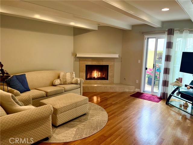 Lovely living room with a marble fireplace, gleaming hardwood floors and access to a patio…