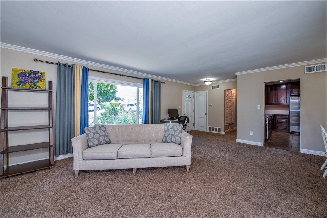 The living room opens up to the dining room to the right, the kitchen and the hallway to the primary bedroom.