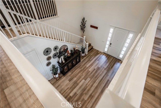 Stunning! Wood laminate upstairs hallway walkway, wood laminate stairway, and wood laminate front entryway, all trimmed in white. Your front entryway with these cathedral ceilings and recessed lighting gives a taste of the elagant show-stopping house inside! Clever hall closet door leads to a closet the length of the staircase is perfect for even more pantry space, or storage for the vacuum and cleaning supplies, etc.