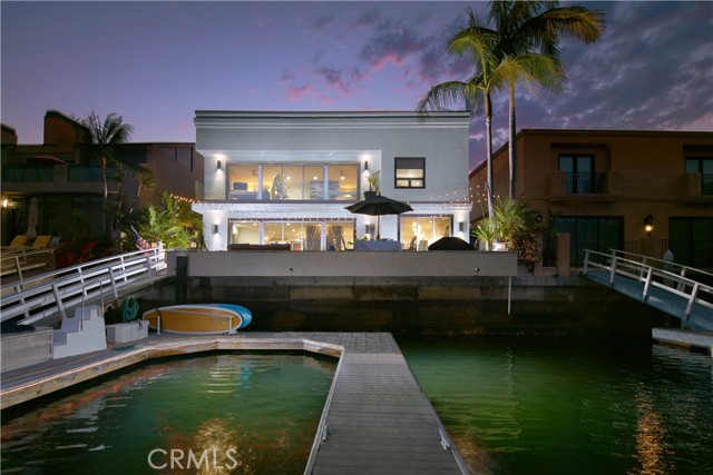 Shimmering water vistas, contemporary architecture, and bespoke interiors thrill the senses at this extraordinary Harbor Island residence. Affording appx. 53' of water frontage and a private 40' dock, the estate's bayfront deck is an idyllic venue for entertaining with an in-ground spa and an open-air fireplace. Design-infused living is evident upon arrival at the home by the custom stainless steel garage doors, patio gate, and custom glass entry doors. Stretching approximately 4,440 square feet, the commodious floorplan presents four ensuite bedrooms and four-and-one-half baths, including a main level suite. Stepping into a lavish foyer entry, the sense of grandeur unfolds before you with a double-height ceiling, floating staircase highlighted by custom stainless steel railings, floor-to-ceiling windows sand-blasted for privacy, gem-inspired custom light fixture by Tom Dixon, and wide-plank wood floors underfoot. Gather in the living area before a book-matched granite fireplace and enjoy sights of the boat studded harbor glistening beyond the sliding glass doors. Open to the waterfront deck is a spacious formal dining room beneath a spectacular custom Bocci chandelier with hand-blown glass. The custom gourmet kitchen boasts a wet bar, waterfall edge onyx countertops and island, sleek custom cabinetry, Wolf range, built-in Sub-Zero refrigerator, separate high top seating, and built-in Sub-Zero wine cooler. Two staircases lead to the second level where three en suite bedrooms, a second fully equipped laundry room, and a versatile fireplace-warmed bonus/game room served by aShimmering water vistas, contemporary architecture, and bespoke interiors thrill the senses at this extraordinary Harbor Island residence. Affording appx. 53' of water frontage and a private 40' dock, the estate's bayfront deck is an idyllic venue for entertaining with an in-ground spa and an open-air fireplace. Design-infused living is evident upon arrival at the home by the custom stainless steel garage doors, patio gate, and custom glass entry doors. Stretching approximately 4,440 square feet, the commodious floorplan presents four ensuite bedrooms and four-and-one-half baths, including a main level suite. Stepping into a lavish foyer entry, the sense of grandeur unfolds before you with a double-height ceiling, floating staircase highlighted by custom stainless steel railings, floor-to-ceiling windows sand-blasted for privacy, gem-inspired custom light fixture by Tom Dixon, and wide-plank wood floors underfoot. Gather in the living area before a book-matched granite fireplace and enjoy sights of the boat studded harbor glistening beyond the sliding glass doors. Open to the waterfront deck is a spacious formal dining room beneath a spectacular custom Bocci chandelier with hand-blown glass. The custom gourmet kitchen boasts a wet bar, waterfall edge onyx countertops and island, sleek custom cabinetry, Wolf range, built-in Sub-Zero refrigerator, separate high top seating, and built-in Sub-Zero wine cooler. Two staircases lead to the second level where three en suite bedrooms, a second fully equipped laundry room, and a versatile fireplace-warmed bonus/game room served by a wet bar reside. The luxurious primary suite showcases stunning views of Promontory Bay and glittering evening lights from its private balcony and features walls of mirrored wardrobes, a freestanding tub, separate shower, and Foscarini lighting. Further highlights include skylights, Restoration Hardware lighting fixtures, specialty tile from Artistic Tile and TileBar, floating built-in cabinetry, a murphy bed in one room, solar-assisted AC, alarm system with video surveillance, and an attached three-car garage. Offering a true connection to the beauty that is Newport Beach's landscape, this trophy estate is a stroll from Lido Marina Village, Fashion Island, five-star resorts, and esteemed schools.