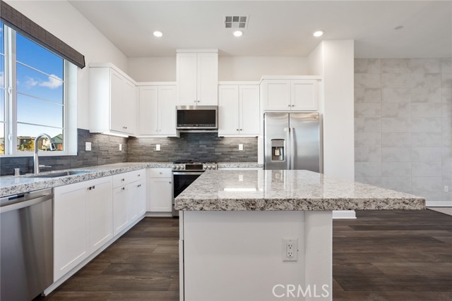 Kitchen with granite counters, white soft close cabinets and designer chosen backsplash