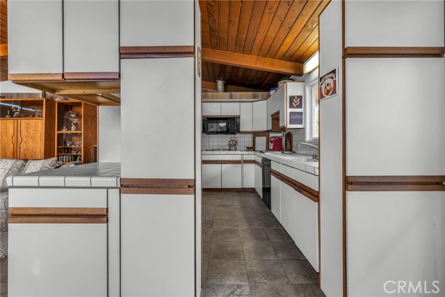 View of the kitchen with tile floor and tiled kitchen counters.