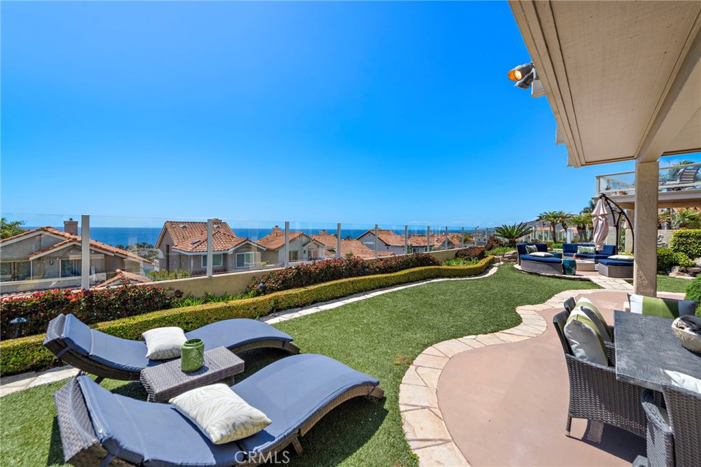 Perched in the exclusive gated community of Regatta, just steps from the sand at Strand Beach, this fully remodeled coastal retreat offers breathtaking 180-degree sit-down ocean views from nearly every level. Situated on one of the largest and most desirable lots in Regatta, the home blends luxury, privacy, and an unbeatable coastal lifestyle. Thoughtfully redesigned from top to bottom with a sleek, modern aesthetic, the home welcomes you on the main level, where the living room, dining area, and kitchen all enjoy a seamless open-concept layout and unobstructed ocean views. The living area features a designer fireplace, built-in cabinetry, a wine refrigerator, and a striking backlit onyx bar, all highlighted by elegant finishes and a dramatic glass-railed staircase.
The adjacent chef’s kitchen is a true showpiece, boasting top-of-the-line appliances, extensive custom cabinetry, and striking waterfall-edge Pental quartz countertops that continue throughout the home, including all bathrooms. The split-level second floor provides exceptional privacy and smart separation of space. Up a half-flight of stairs, the primary suite serves as a serene sanctuary, complete with double doors opening to a private balcony with panoramic ocean views, rich hardwood flooring, and a spa-inspired en-suite bath featuring a walk-in shower with custom tile, a soaking tub overlooking the Pacific, and dual vanities.
Upstairs from the primary suite, you'll find two additional bedrooms and a full bath—perfect for guests, family, or a home office setup. Throughout the home, abundant natural light, modern design elements, and premium materials create an effortless sense of elegance and comfort. Outside, the generously sized backyard is beautifully landscaped with mature greenery, offering a private and peaceful setting for outdoor dining, entertaining, or enjoying the ocean breeze. Located just a short stroll from world-class beaches, fine dining, and the vibrant Dana Point Harbor, this turnkey residence offers the very best in modern coastal living—elevated, effortless, and truly exceptional.