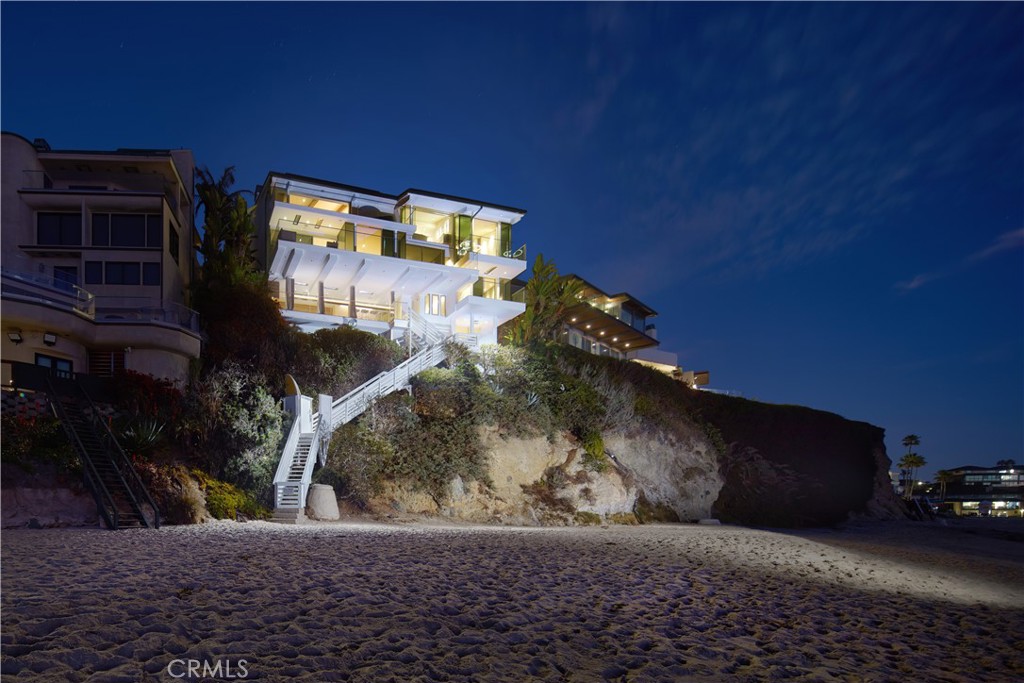 Perched above the sand in Laguna Beach’s most sought-after shoreline, this architectural masterpiece offers 79' of view frontage with breathtaking panoramic ocean and coastline views. Boasting an unparalleled array of luxurious amenities, the beachfront home features private steps descending to the shoreline, providing effortless access to one of Laguna’s most coveted beaches. Spanning approximately 3,541 square feet across a split-level layout, the residence encompasses three bedrooms (including a tranquil meditation room), two offices, and three-and-one-half baths. At its heart lies a SieMatic kitchen—a chef’s dream outfitted with quartz countertops, Gaggenau and Subzero appliances, dual dishwashers, and sinks. A custom bar area with Subzero fridge/freezer drawers enhances entertaining, while expansive windows frame mesmerizing ocean views, bathing the home in natural light. Exceptional details include a glass-enclosed refrigerated wine display with storage for 216 bottles and Isokern fireplaces in the living room and primary suite. Approximately 1,200 square feet of outdoor decks and terraces include features such as Infratech ceiling heaters, an outdoor lounge with bar, a water element, living wall, and firepits, creating numerous peaceful verandas. The primary suite is a private haven complete with heated towel racks, and exquisite finishes. Exterior highlights include limestone and porcelain details, Fleetwood windows, a copper roof, and EnduroShield-treated glass railings. Expansive decks and terraces extend the living space outdoors, providing an idyllic setting for alfresco dining or moments of tranquility with the sound of the waves. Situated within the exclusive gated community of Lagunita, the home blends privacy with proximity to the renowned Montage Resort. Additional highlights include an elevator, seller-owned solar, a two-car garage with vaulted ceilings, dual washer/dryer laundry setups, air and water purification systems, and advanced security. With private access to Victoria Beach, 14 Lagunita Drive is a true representation of elevated coastal living, offering a daily retreat from the ordinary.