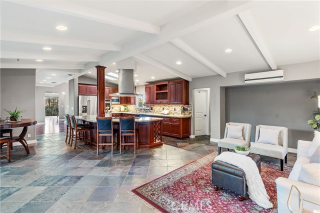The family room area of the great room with vaulted open beamed ceilings, warm PV Stone fireplace, slate floors, recessed lighting.