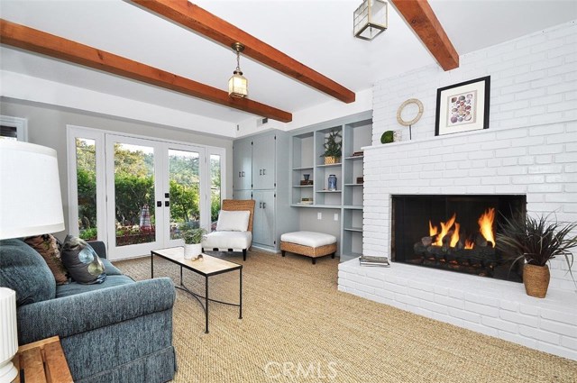 This third living space downstairs boasts seagrass carpet, exposed wood beams, built ins, and opens to the outdoor living space.