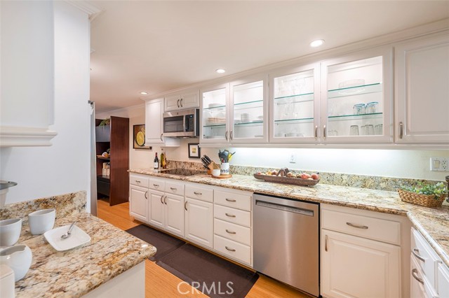 Beautiful updated kitchen with custom cabinetry with glass fronts, granite countertops, sleek glass cooktop and SS microwave.