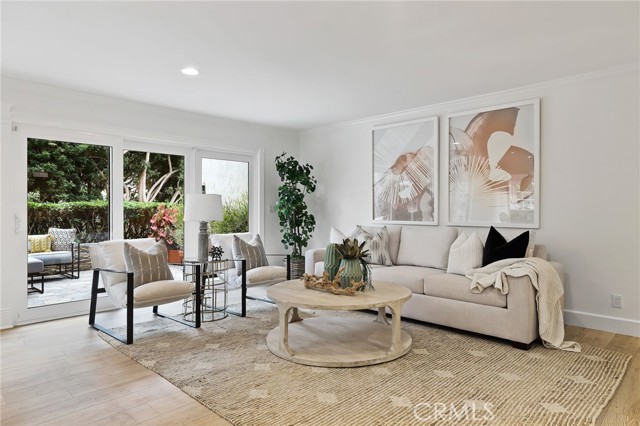 The expansive living room features a stone fireplace, complemented by built-ins, adjacent to a formal dining room – all seamlessly opening onto the wrap-around back patio, offering a side view of the Back Bay.