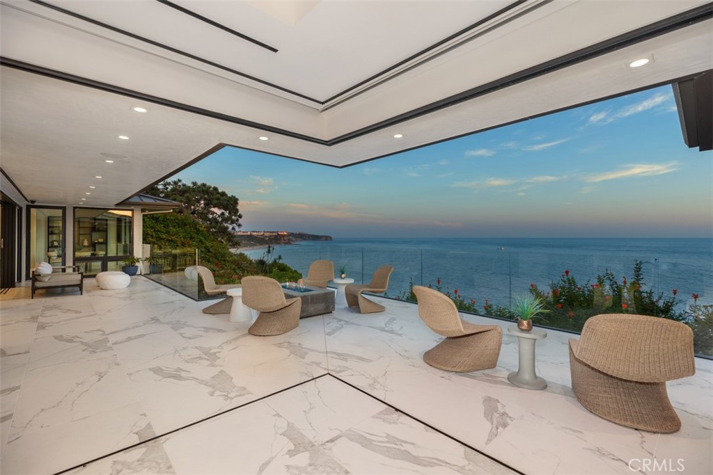Commanding the front row of the guard-gated Monarch Bay, this bluff-top estate offers an unparalleled lifestyle. Brand new in 2019 and completely reimagined for contemporary luxury, it boasts expansive ocean vistas, capturing ethereal sunsets and whitewater views from every angle. Massive Neolith 59” tiles grace the entire main floor, making a powerful statement of sophistication. The gourmet kitchen is a modern marvel, featuring top-of-the-line Sub-Zero and Wolf appliances, quartz countertops, and a generous 8-seater island perfect for effortless entertaining. Retreat to the primary suite with dual spa-like bathrooms adorned with decorative glass tile and boutique-style walk-in closets. Three en suite bedrooms provide ample guest accommodations, and the 4-car garage, equipped with ingenious Carousel car lifts, offers secure space for your prized collection.  Outside, unwind in the custom spa nestled in the private interior courtyard, or enjoy evenings around the fire pit on the rear deck, taking in the stunning sunsets over the Pacific. Monarch Bay delivers unmatched resort-style amenities, including tennis courts and the esteemed Beach Club with oceanfront dining and direct beach access. Residents also enjoy privileges at the nearby Waldorf Astoria, enhancing the exclusive lifestyle this community offers.  This estate is just minutes from the charms of Dana Point and Laguna Beach, world-class golf at Monarch Beach Links, high-end resorts, shopping, and Dana Point Harbor. Yet, it remains a tranquil sanctuary, a private domain from which to survey your coastal kingdom. For the most discerning owner, this is more than a home—it is a legacy. A testament to your achievements and refined tastes. Seize this opportunity to claim your place at the pinnacle of coastal luxury living.