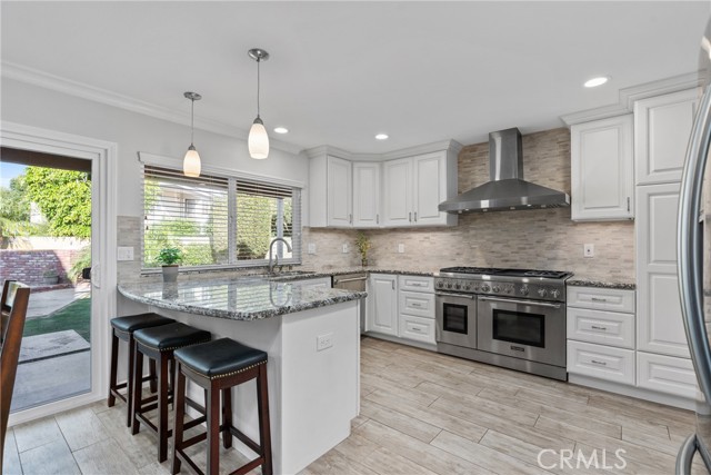 The efficient layout flows seamlessly into a beautiful, remodeled kitchen that has a large peninsula with a breakfast bar and pendant lighting!