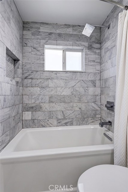 Remodeled shower in bath with subway tile and rainfall shower head.