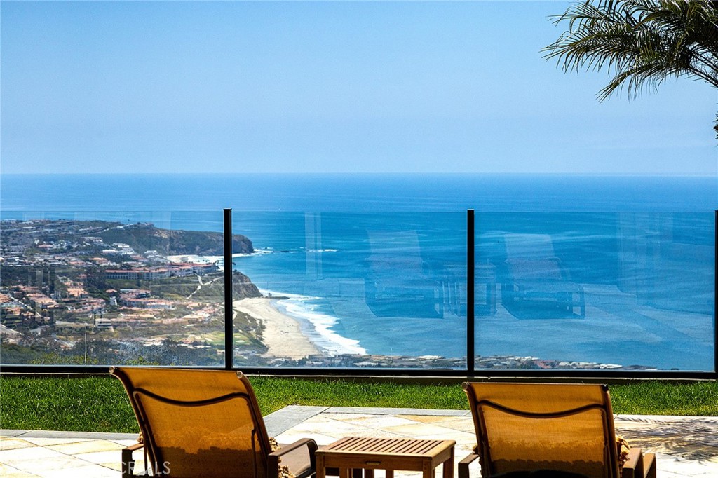 Perched high above the Pacific in the exclusive guard-gated community of Monarch Point, this elegant coastal home offers sweeping panoramic views of the ocean, coastline, and city lights. Thoughtfully designed for both comfort and entertaining, the open-concept floor plan is filled with natural light and features soaring ceilings, a spacious living room with fireplace, formal dining area, and a welcoming family room that opens to the beautifully landscaped backyard. The gourmet kitchen includes premium appliances, custom cabinetry, and a large center island, ideal for gatherings. The main-level primary suite offers privacy and convenience, while additional bedrooms upstairs provide ample space for family or guests. A large dedicated office provides a quiet and functional space for working from home. The serene backyard features a private spa surrounded by lush landscaping—an ideal retreat to relax and unwind. Situated at the end of a quiet cul-de-sac, the home also includes its own gated driveway, offering added privacy and security.  Monarch Point residents enjoy exclusive amenities including lighted tennis courts, a clubhouse, pool, spa, and scenic hiking trails with sweeping ocean vistas. Located just minutes from world-class resorts, beaches, fine dining, shopping, and top-rated schools, this home embodies the best of Southern California coastal living.