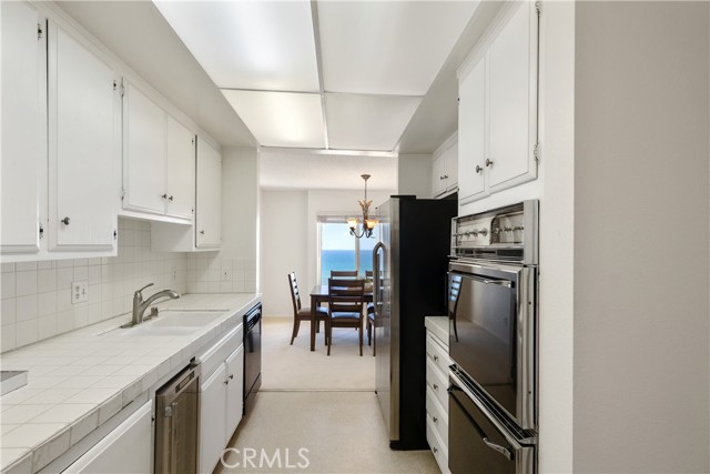 The kitchen is appointed with refrigerator, range, dual-ovens, microwave, dishwasher, wine refrigerator, white cabinetry, ample storage and large panty.